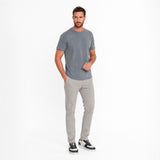 Man wearing a gray t-shirt and light gray pants on a white background