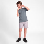 A young boy modeling a short-sleeve crewneck t-shirt in slate gray and light gray shorts, paired with black sneakers