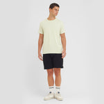 Man wearing a light yellow t-shirt and black shorts on a white background