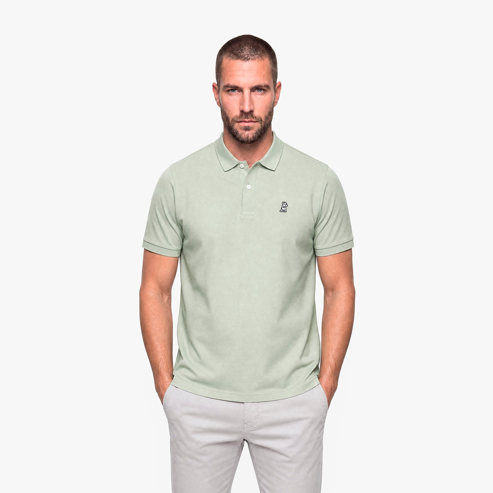 Man wearing a light green polo with a white embroidered logo on a white background