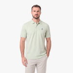A man wearing a light green polo shirt with a small embroidered logo on the left chest