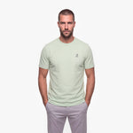 Man wearing a light green t-shirt with a white logo on a white background