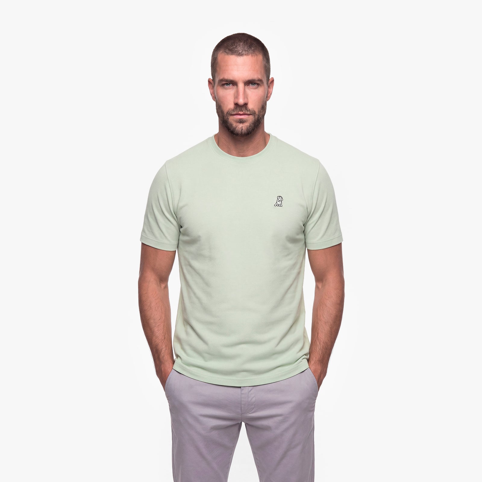 Man wearing a light green t-shirt with a white logo on a white background