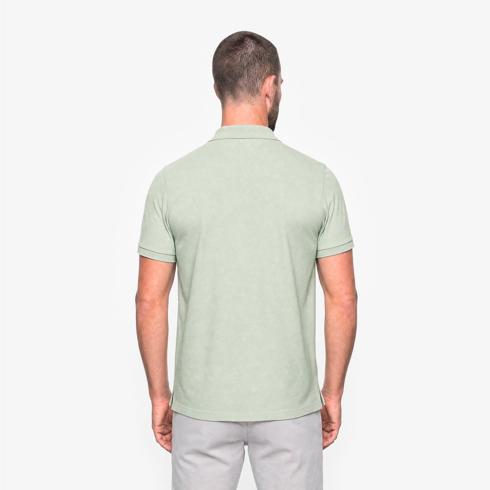 Man wearing a light green polo shirt on a white background