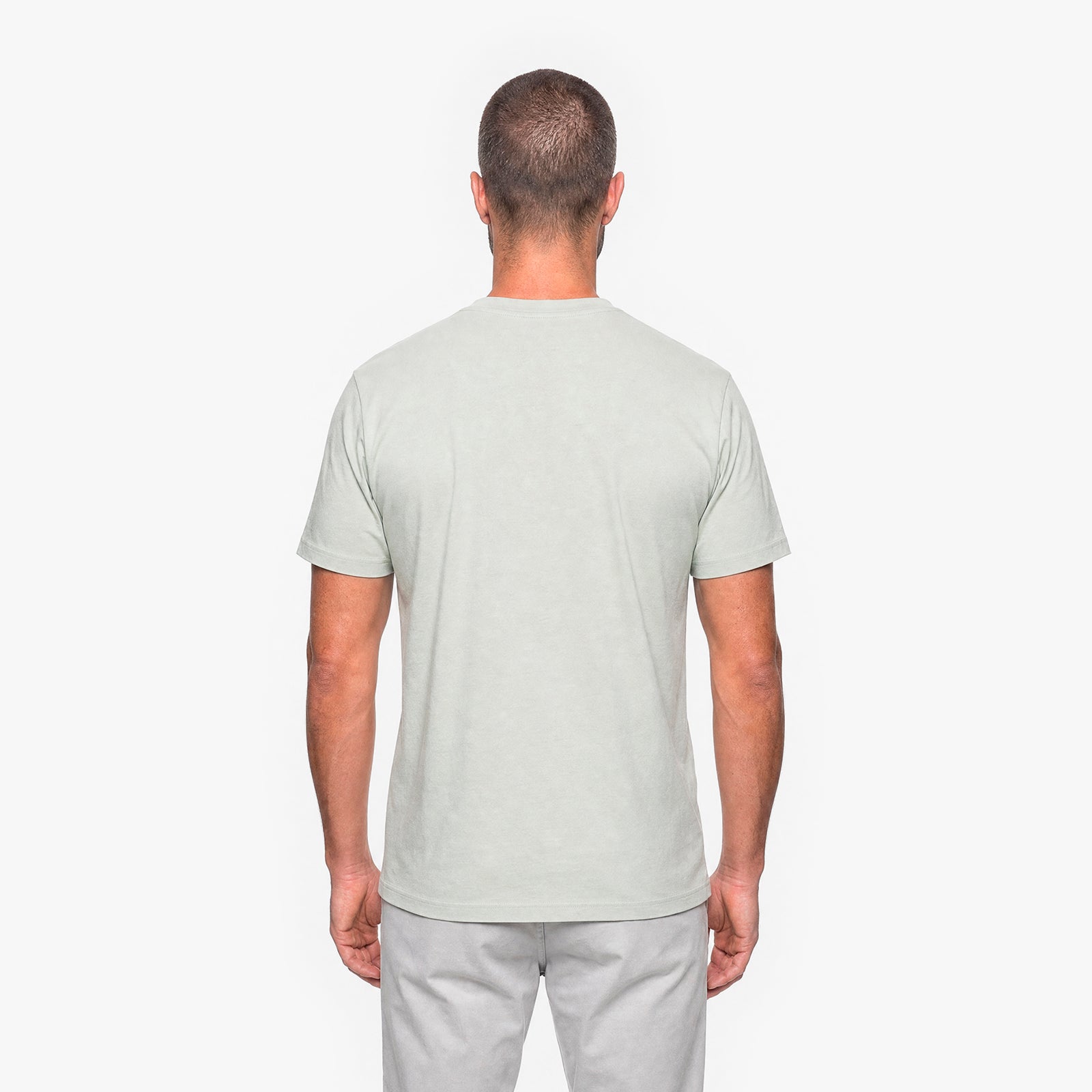 Man wearing a light gray t-shirt and pants on a white background