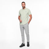 Man wearing a light green polo shirt and gray pants on a white background