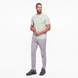 Man wearing a light green t-shirt and gray pants on a white background
