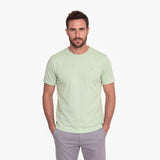 Man wearing a light green t-shirt and gray pants on a white background