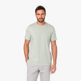 Man wearing a light green t-shirt and gray pants on a white background