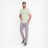 Man wearing a light green t-shirt and gray pants on a white background