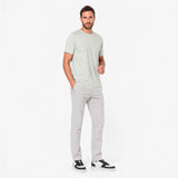 Man wearing a light gray t-shirt and pants on a white background