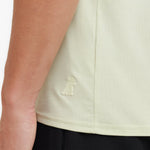 Close-up of a light green sleeveless top with a logo on a person wearing it.