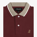 Close-up of the collar and buttons of the maroon polo shirt: A detailed view of the beige collar with white piping, showing the button placket and the small embroidered dog logo on the chest.