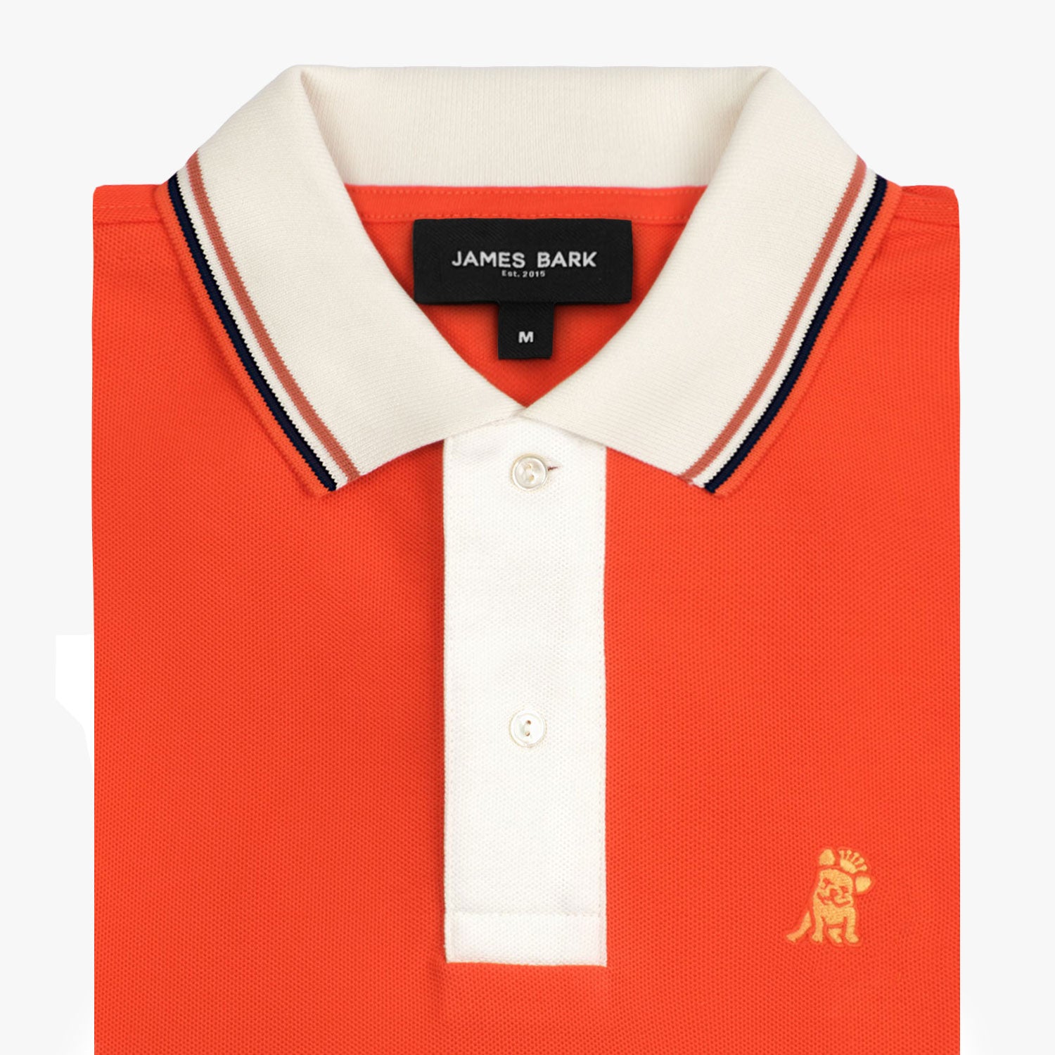 Close-up of the collar and upper part of the orange polo shirt, showing the buttons and the small golden embroidered logo on the chest.
