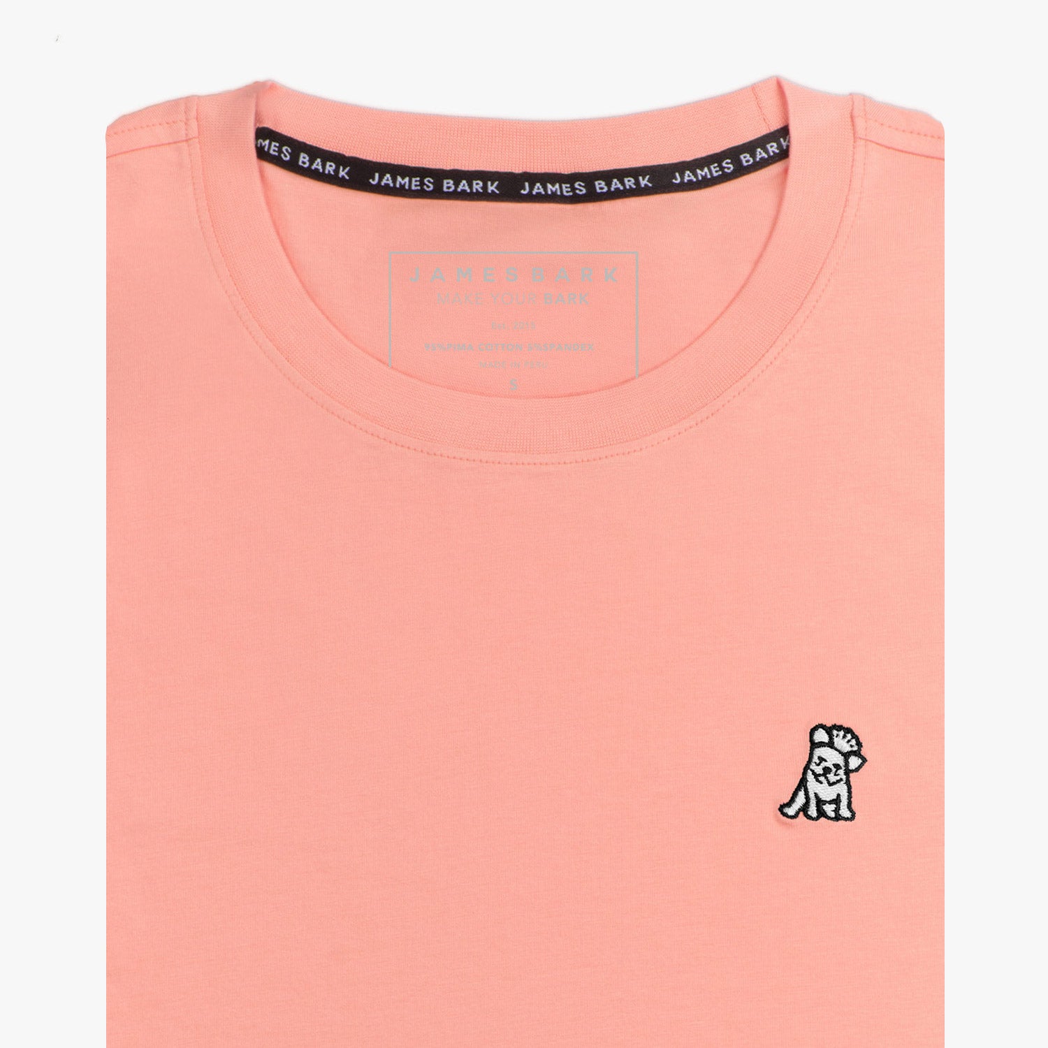 Close-up of the light pink t-shirt showing the crew neckline and a small embroidered animal logo on the left chest.