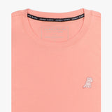 Close-up of the light pink t-shirt showing the crew neckline and a small embroidered animal logo on the left chest.