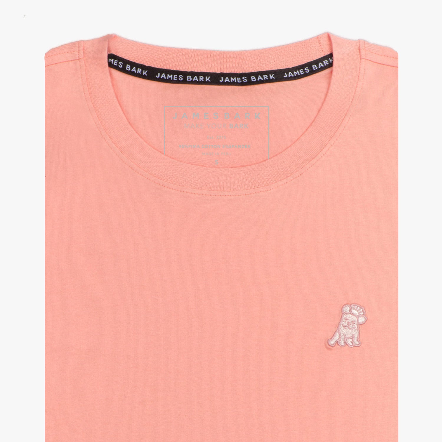 Close-up of the light pink t-shirt showing the crew neckline and a small embroidered animal logo on the left chest.