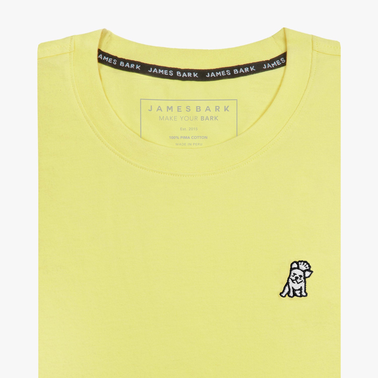 Close-up of the light yellow t-shirt showing the crew neckline and a small embroidered animal logo on the left chest.