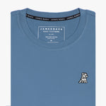 Close-up of the blue t-shirt showing the crew neckline and a small embroidered animal logo on the left chest.