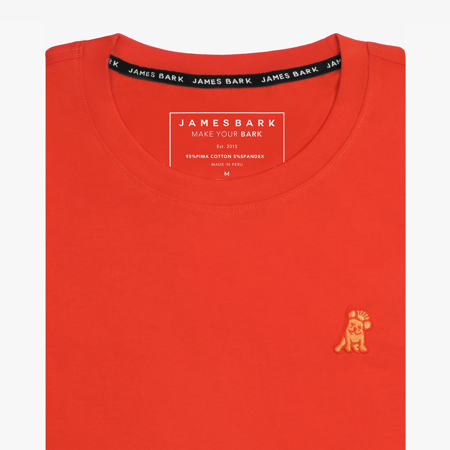 Close-up of the orange t-shirt showing the crew neckline and a small embroidered animal logo on the left chest.