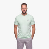 Man wearing a light green t-shirt with a white embroidered logo on a white background