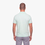 Man wearing a light green polo shirt on a white background