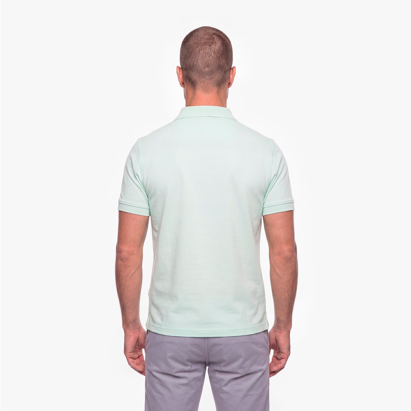 Man wearing a light green polo shirt on a white background