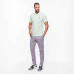 Man wearing a light green polo shirt and gray pants on a white background