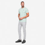 Man wearing a light green t-shirt and gray pants on a white background