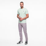 Man wearing a light green t-shirt and gray pants on a white background