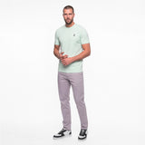 Man wearing a light green t-shirt and gray pants on a white background