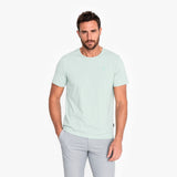 Man wearing a light green t-shirt and gray pants on a white background
