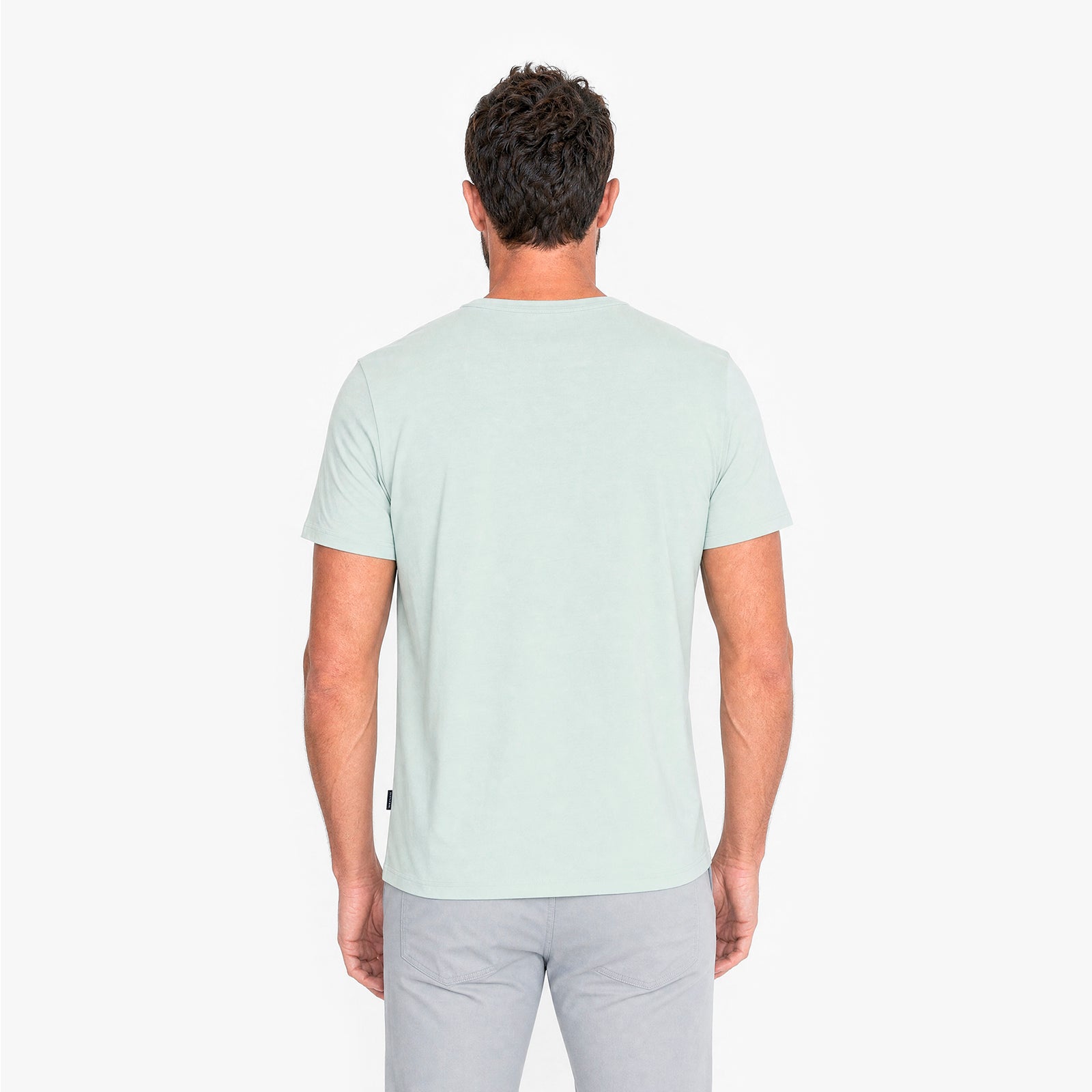 Back view of a man wearing a light green t-shirt on a white background