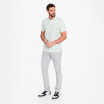 Man wearing a light green shirt and gray pants on a white background