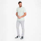 Man wearing a light green shirt and gray pants on a white background