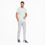 Man wearing a light green t-shirt and gray pants on a white background