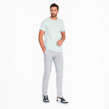 Man wearing a light green t-shirt and gray pants on a white background