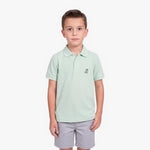 A young boy modeling a light mint green polo shirt with a small embroidered logo on the left chest