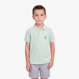 A young boy modeling a light mint green polo shirt with a small embroidered logo on the left chest