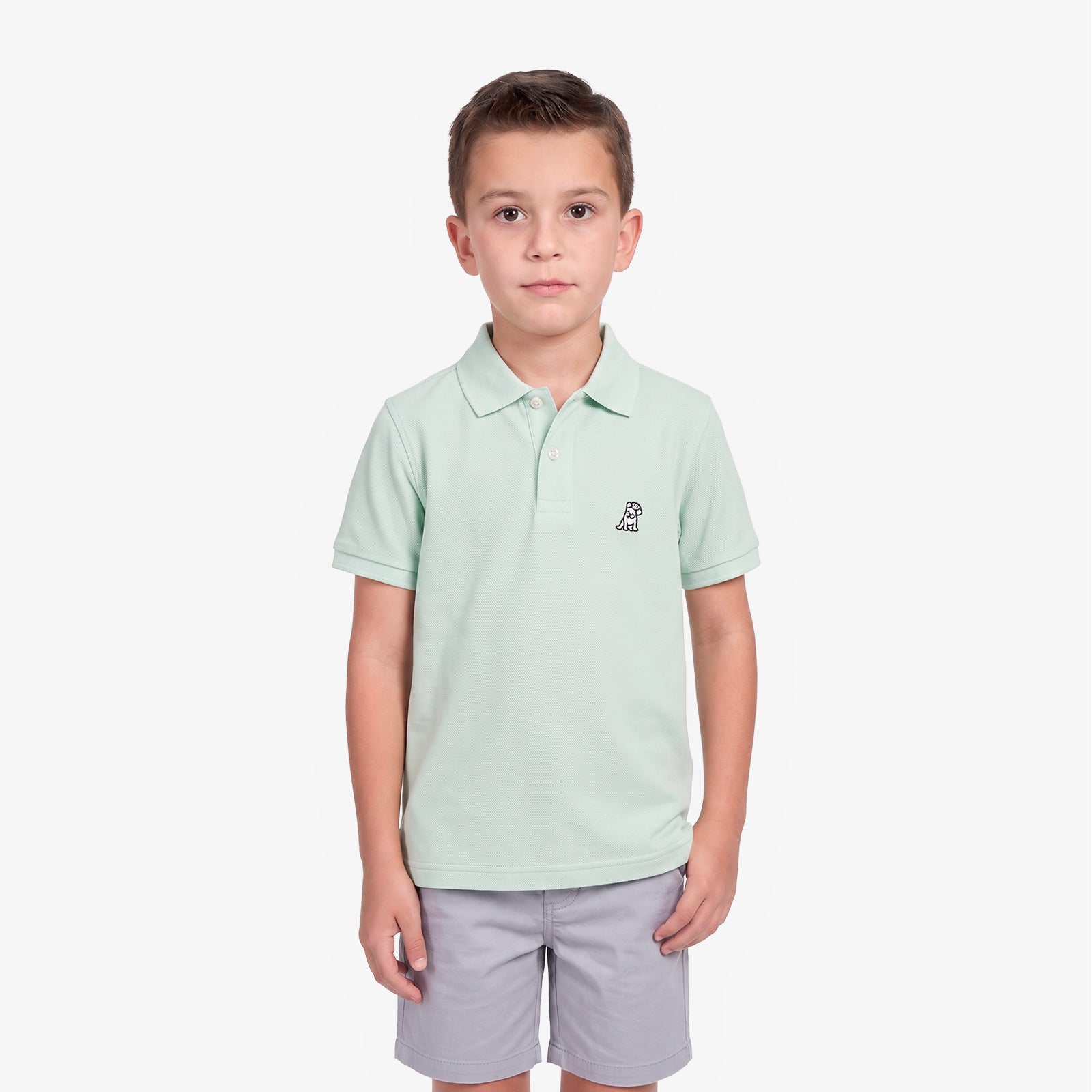 A young boy modeling a light mint green polo shirt with a small embroidered logo on the left chest