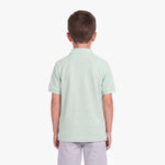A child viewed from the back, wearing a light mint green polo shirt and light gray pants
