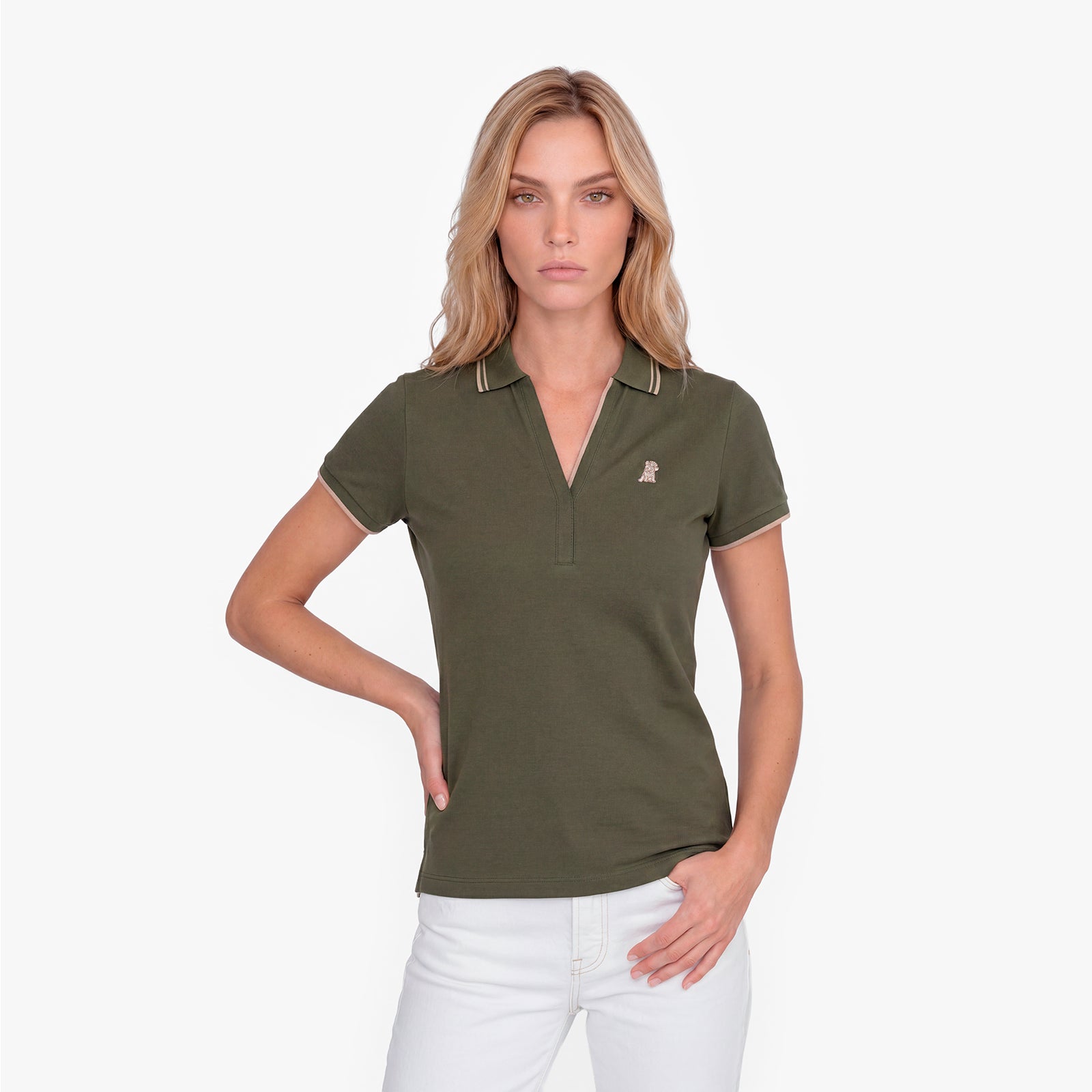 Woman wearing a green polo with an embroidered dog logo on a white background