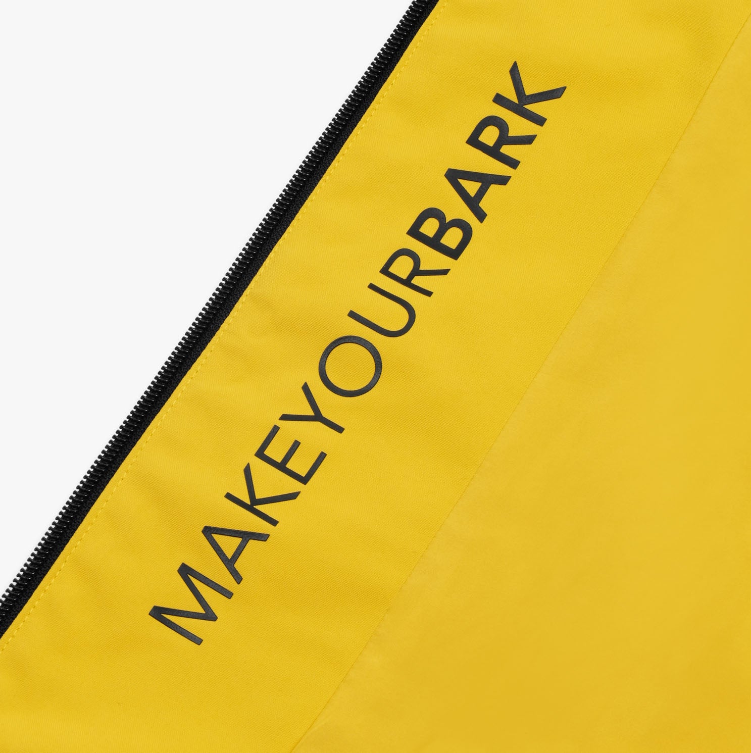 A close-up detail of a yellow jacket featuring the bold black text "MAKEYOURBARK" printed along the inside seam, near a black zipper. The text stands out against the vibrant yellow fabric, showcasing a personalized branding element on the interior of the jacket. The zipper adds a sleek, functional touch to the design.