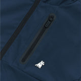 Close-up of a navy blue jacket featuring a black, waterproof zipper on a chest pocket. Below the zipper, there is a small embroidered white dog wearing a crown, adding a playful detail to the design.