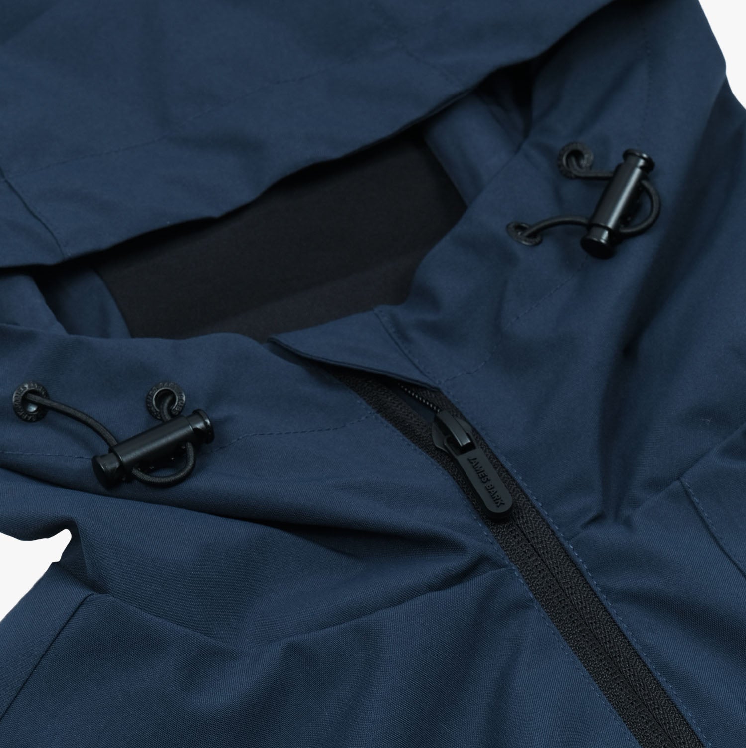 The image shows a close-up of a dark navy blue jacket with a zipper and adjustable hood. The hood has elastic drawstrings with plastic toggles for tightening, and the zipper features a sleek pull tab. The material appears to be durable, likely water-resistant, and designed for outdoor use or activewear