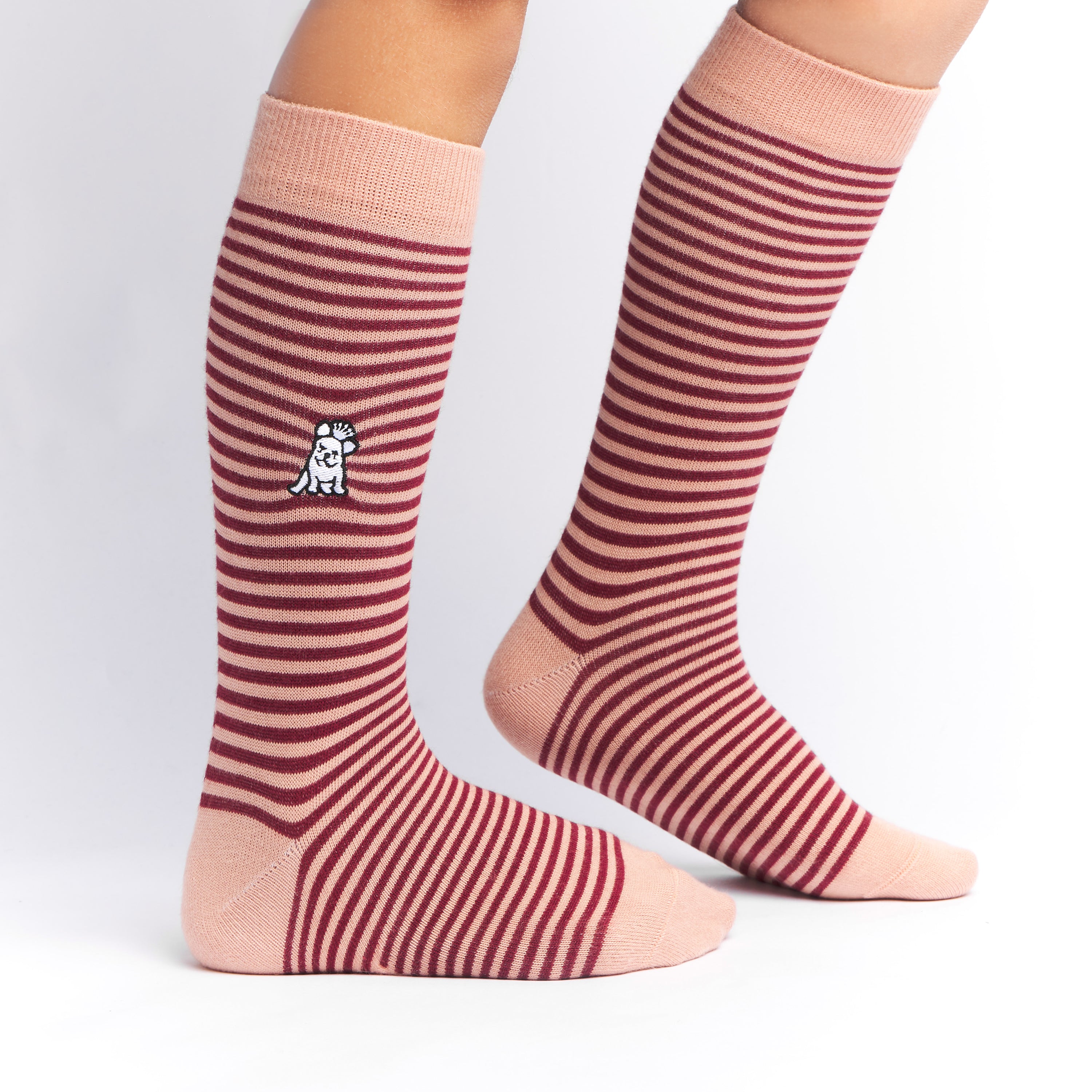 Brown and pink striped mid-calf socks with a solid pink cuff, heel, and toe, featuring a small dog graphic near the ankle and the text 'JAMES BARK' near the toe, shown worn on a person’s feet.