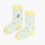 A pair of light blue mid-calf socks with a yellow cuff, heel, and toe, featuring a lemon pattern and a small dog graphic near the ankle. The text 'JAMES BARK' is printed in yellow near the toe. The socks are laid flat on a white surface.