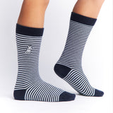 Navy blue and white striped mid-calf socks with a solid navy cuff, heel, and toe, featuring a small dog graphic near the ankle and the text 'JAMES BARK' near the toe, shown worn on a person’s feet.