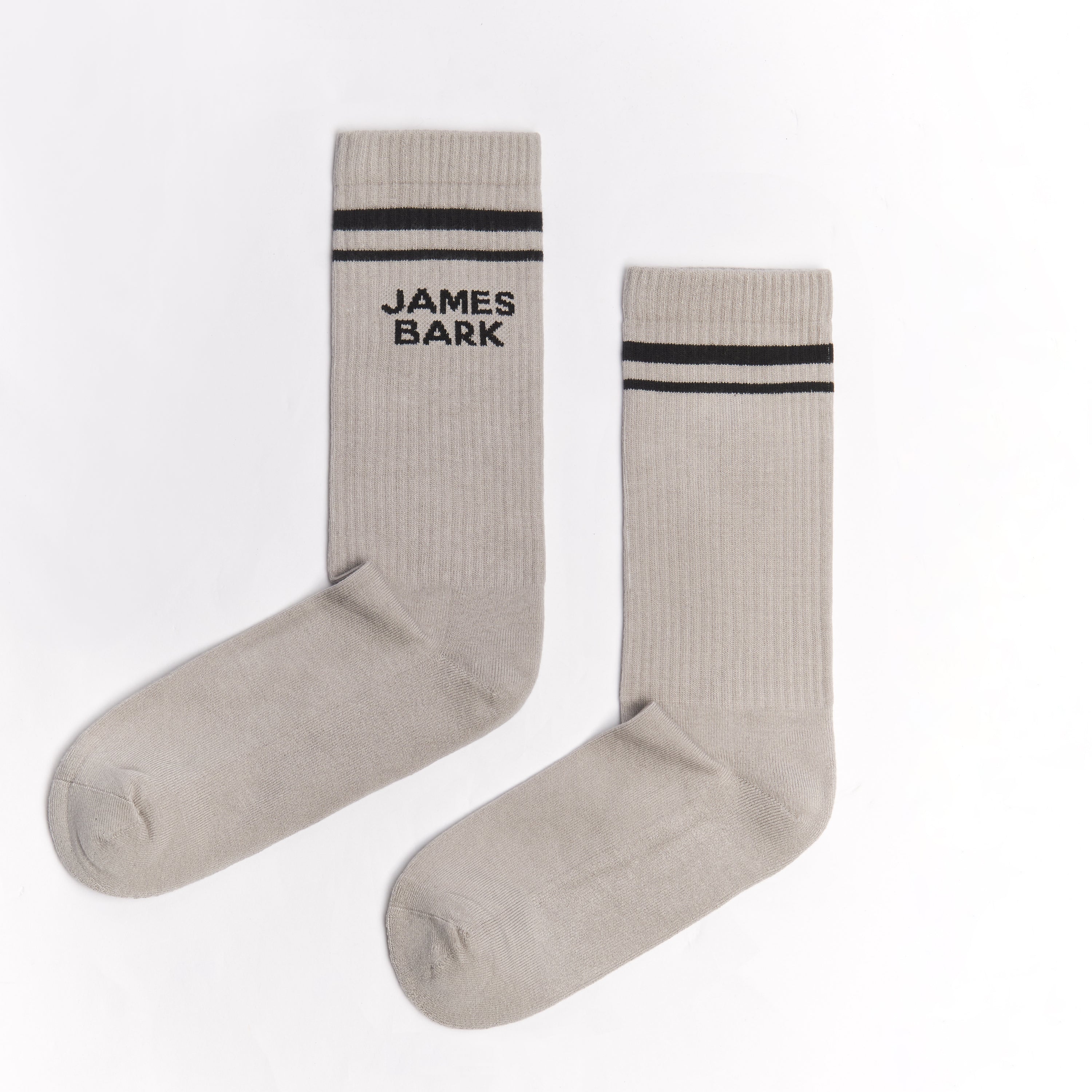 A pair of light gray mid-calf socks with two black stripes at the top and the text 'JAMES BARK' printed in black near the ankle. The socks are laid flat on a white surface.