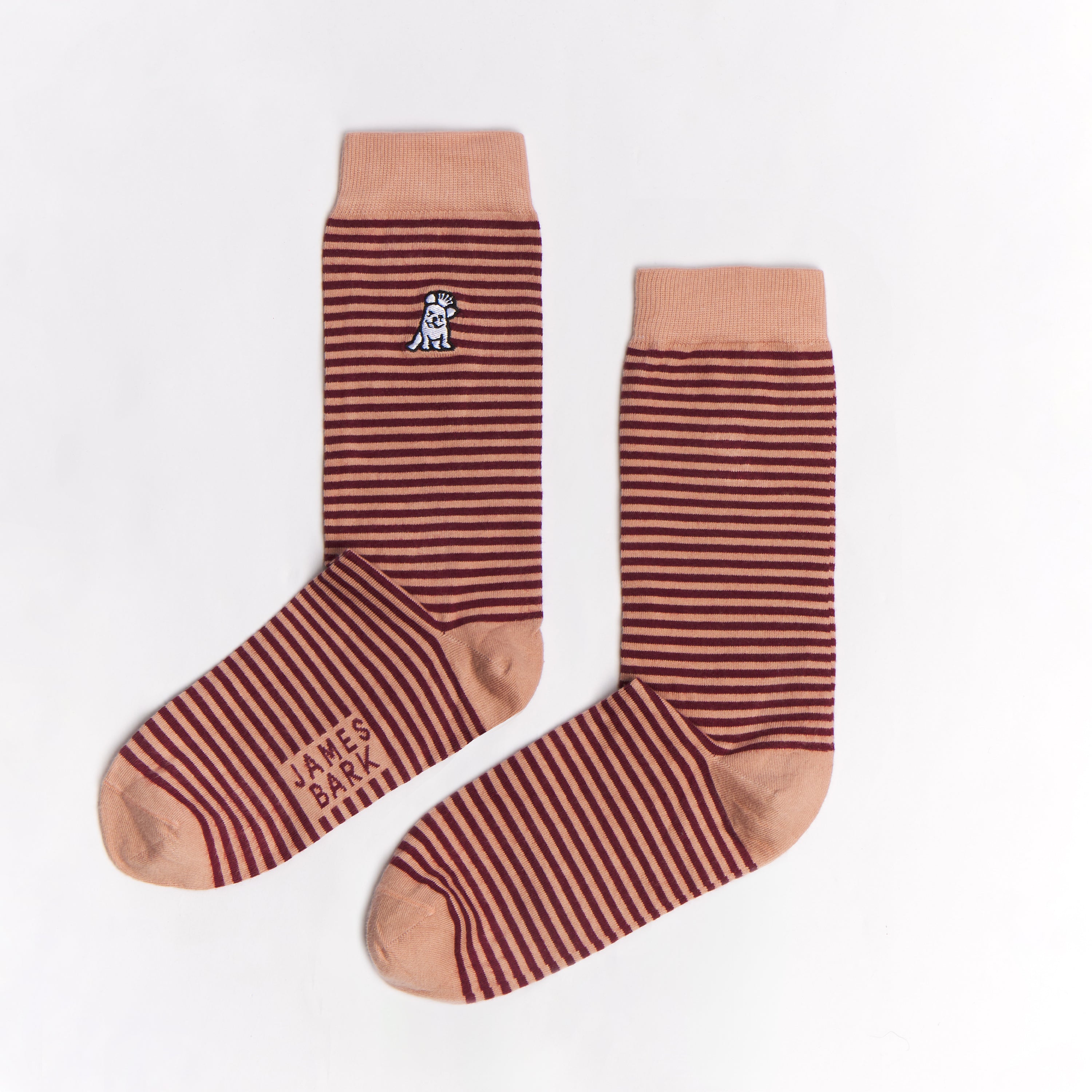 A pair of brown and tan striped mid-calf socks with a solid tan cuff, heel, and toe. There is a small dog graphic near the ankle, and the text 'JAMES BARK' is printed near the toe. The socks are laid flat on a white surface.